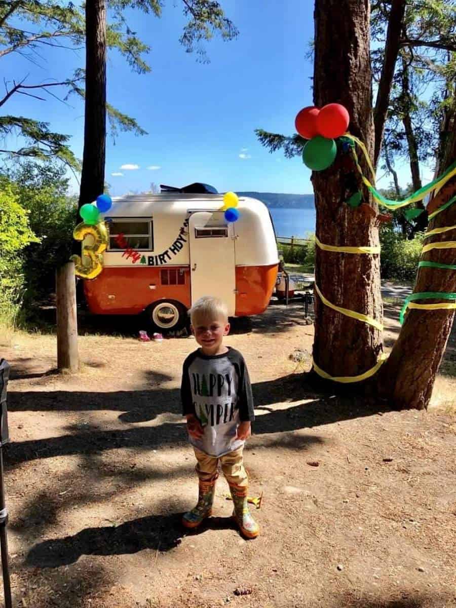 Birthday boy standing in front of vintage Boler camper