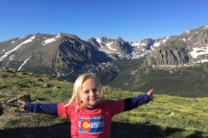 girl with arms outstretched in front of Rocky Mountains