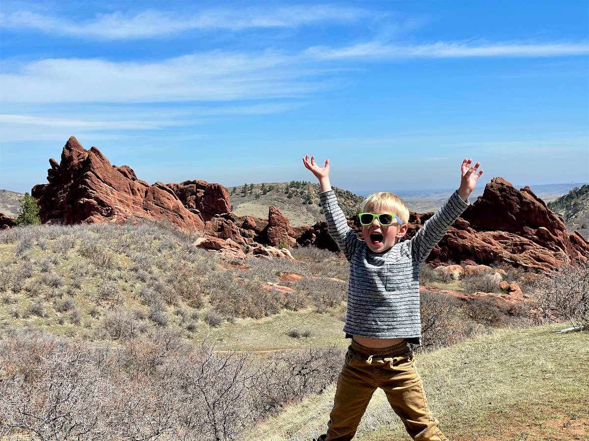 boy with arms up at top of hike