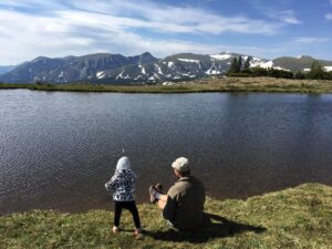 dad and girl throwing rocks in pond in Rocky Mountain National Park