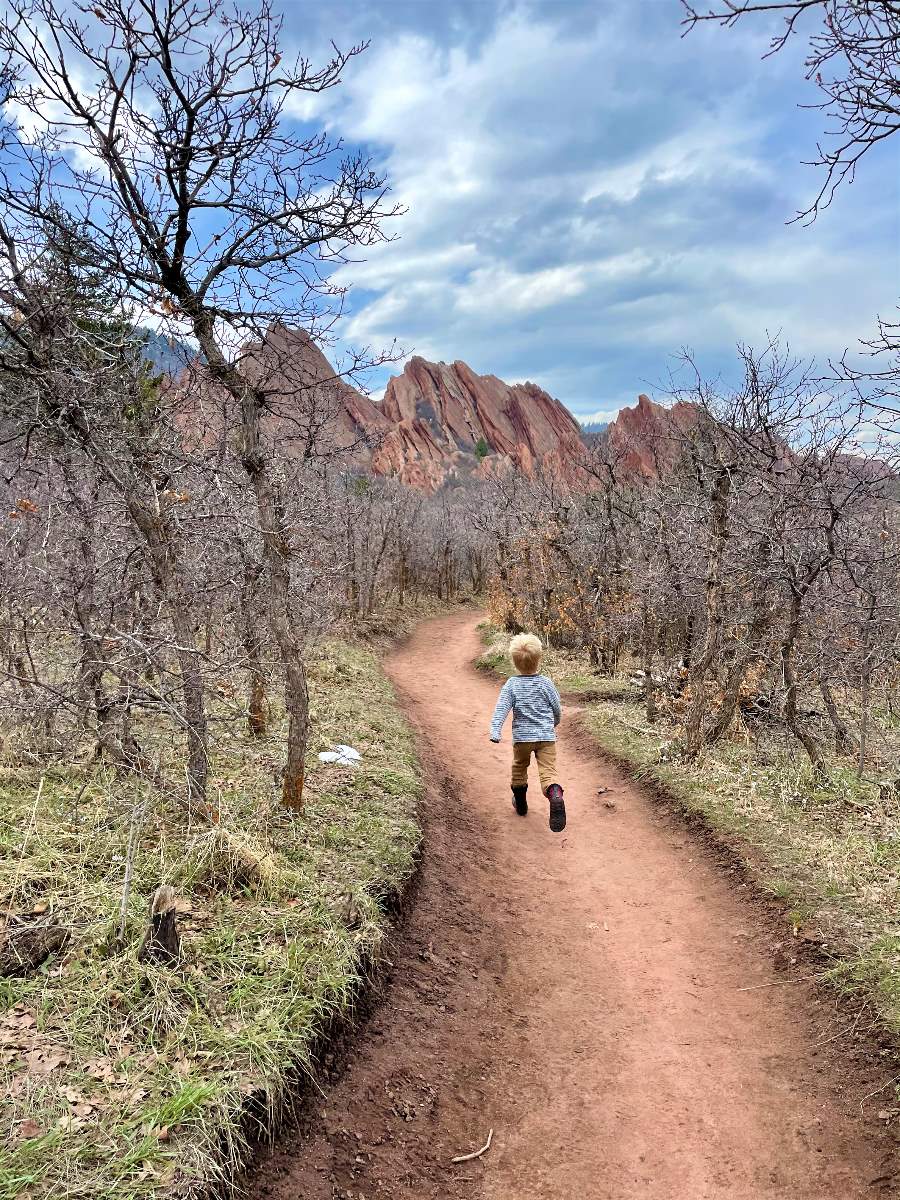 boy running on trail with red rocks