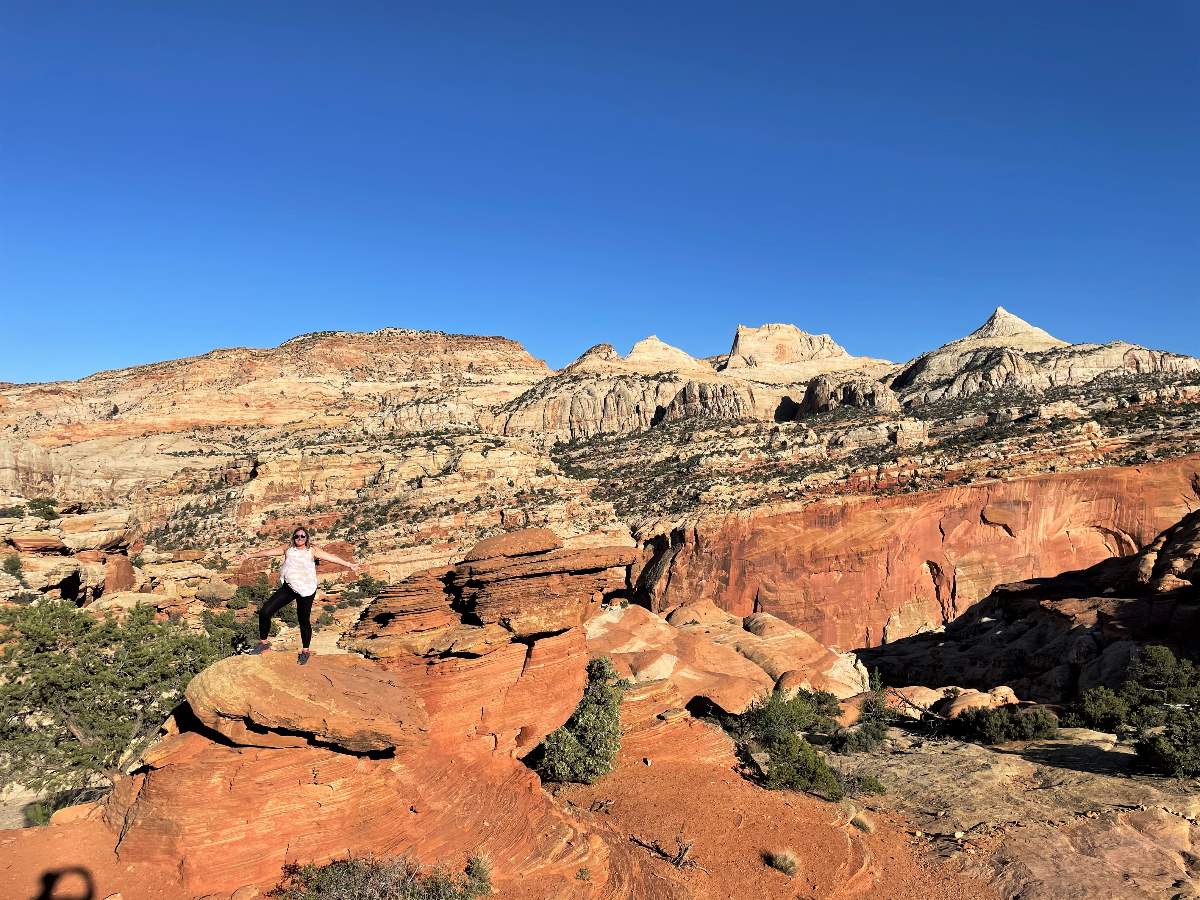 woman standing on rock with Capitol Reef view behind