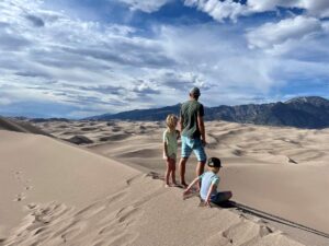 dad and kids looking over edge of dune field