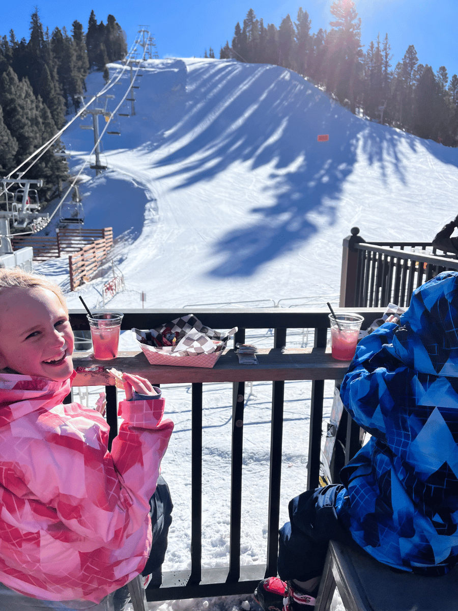 Kids eating lunch on deck with ski hill in the background