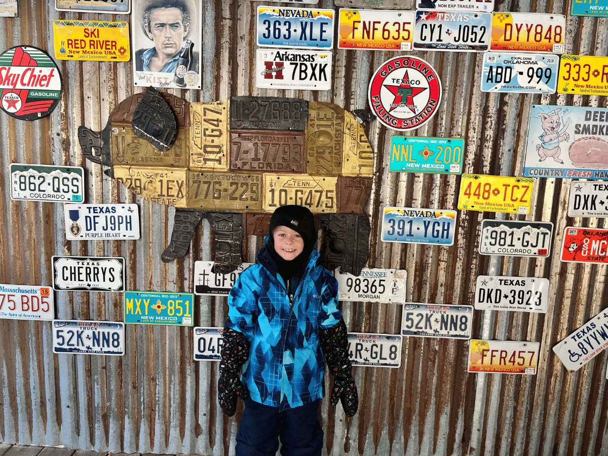 Boy in front of license plates on wall