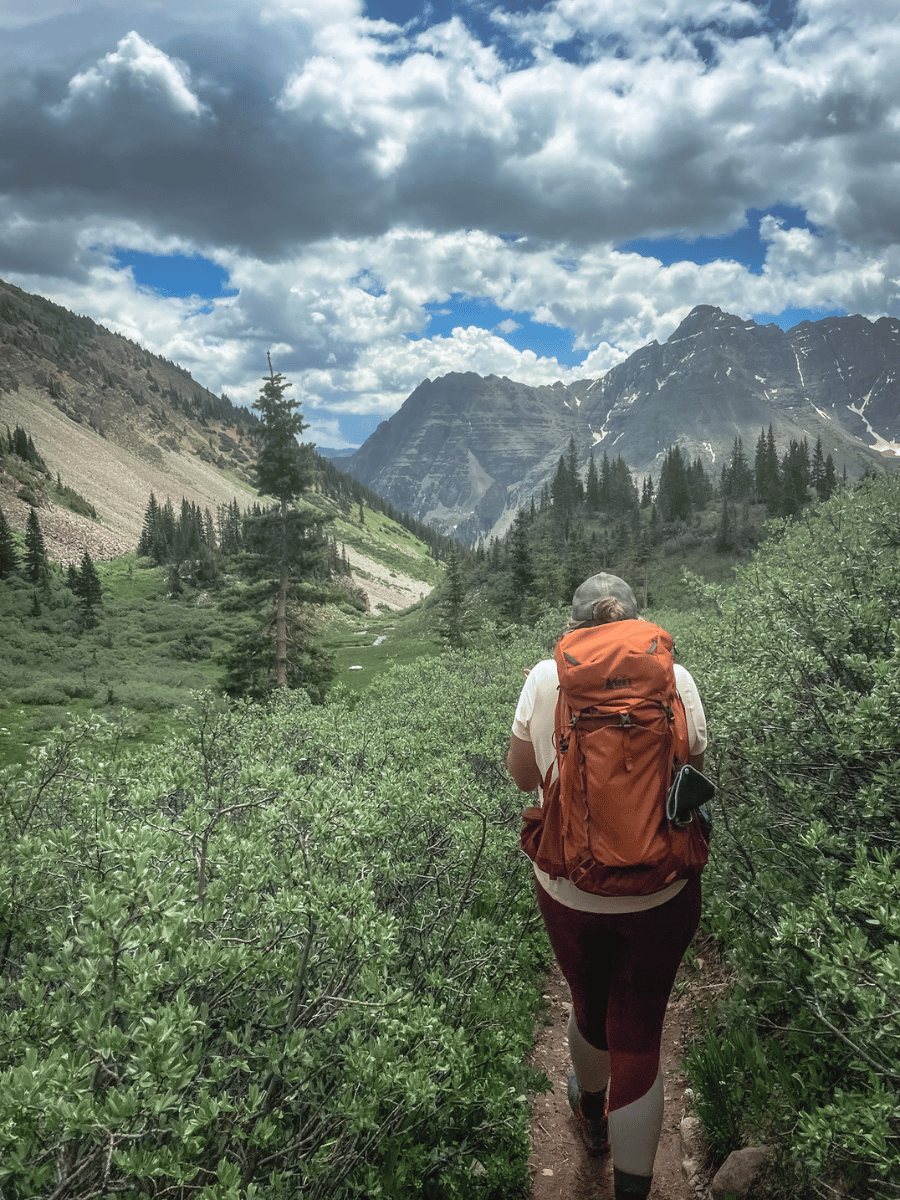 Woman hiker from behind carrying backpack in the mountains