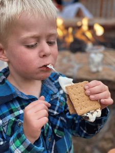 boy eating a s'more by a campfire