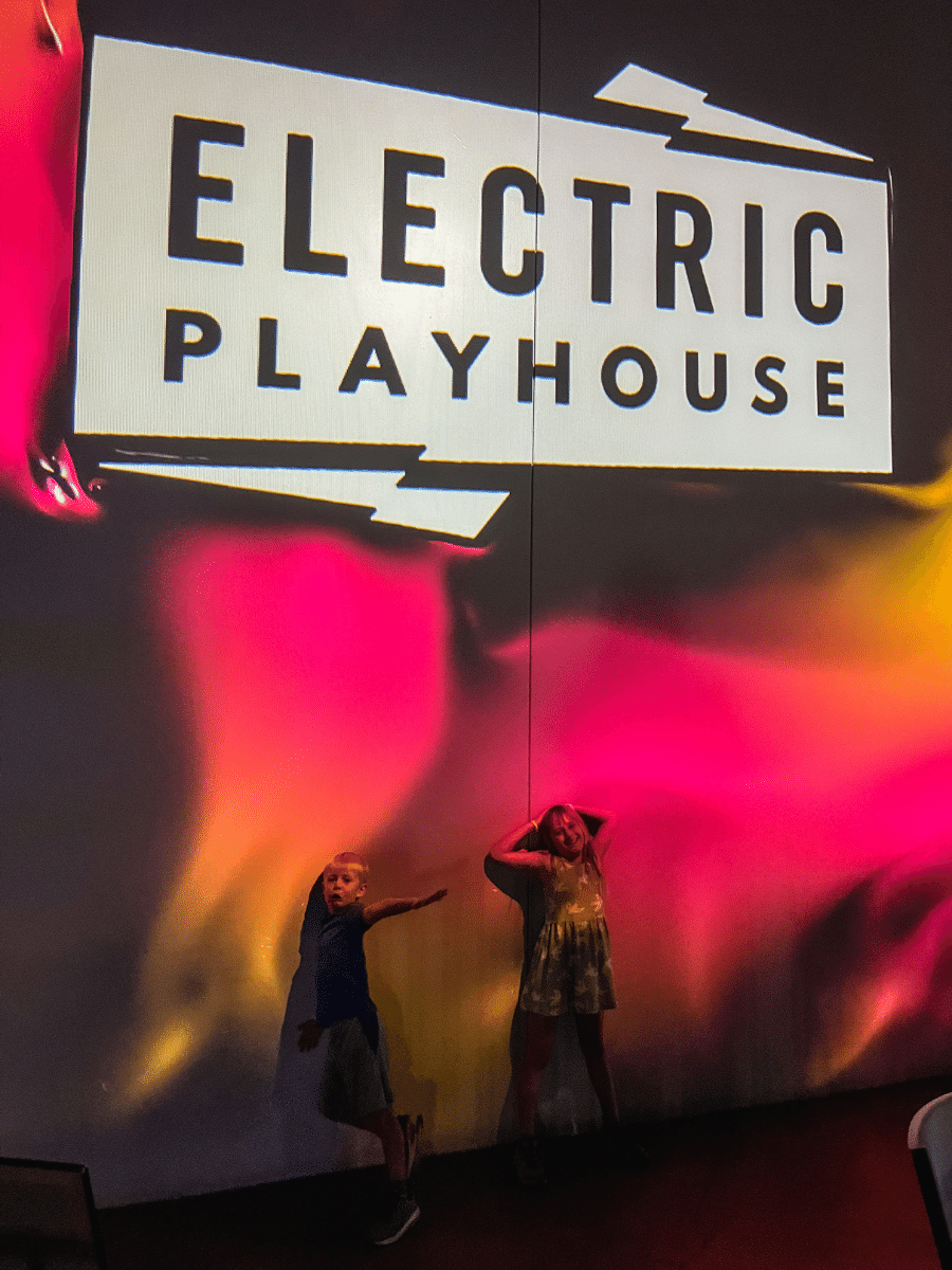 Kids under Electric Playhouse sign