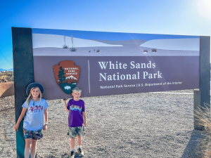 Kids standing in front of White Sands National Park sign